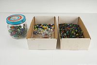 Shows the entire lot including a jar of marbles and two boxes filled with assorted marbles.
