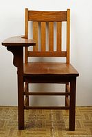 Front view showing vertical slat backrest and attached writing surface on right side.