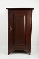 Front view of the antique wooden side cabinet showing single paneled door and metal handle with lock.