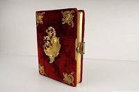Full view of the closed antique photo album showing red velvet cover and gold clasp on the side.