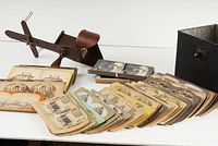 Wooden stereoscope viewer with many stereoscopic photo cards spread out in front