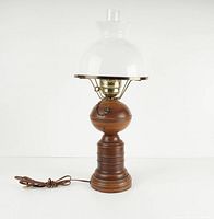 Full view of vintage electric table lamp with wooden base, brass hardware, and clear glass chimney.
