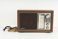 Front view of vintage Panasonic radio showing wood grain finish, speaker grille, and control panel with tuning and knobs.