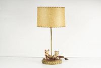 Full view of the vintage Mid Century Modern table lamp with the fiberglass shade and two carved cat figurines on the base.