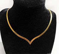 Necklace displayed on a black velvet bust showing front V-shaped design and chain form