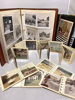 Two large photo albums and nine small accordion-style photo albums with various vintage photos laid out around them