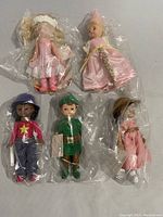 Photo of five Madame Alexander mini dolls, all in protective plastic bags. Dolls include Peter Pan, 100th Anniversary Teddybear Girl, Cool Cathy, Rapunzel, and Pink Fairy.