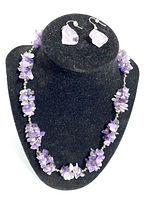 Necklace and earrings set displayed on black stand, highlighting amethyst clusters and single stone earrings.