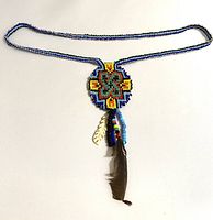 Full view of beaded necklace with feather and medallion laid flat showing length and design