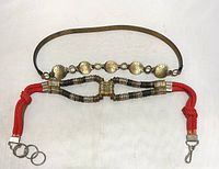 Close-up view of bronze colored metal clip belt with red braided rope and metal coil accents, showing clip closures.