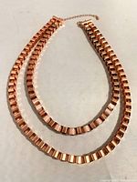 Copper double strand necklace laid flat on a surface showing both strands with rectangular links.