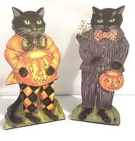Front view of two Halloween cat stand ups featuring detailed painted costumes and holding jack-o'-lantern buckets.