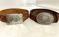 Two belts side by side, showing heart and horse head buckles