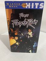 Front view of the VHS tape cardboard sleeve showing the Purple Rain title, Warner Bros Hits branding, and image of Prince.