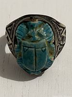 Front view of sterling silver ring showing blue scarab centerpiece and ornate designs on band.