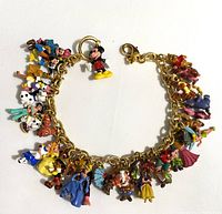 Top-down view of gold-plated link bracelet arranged in a circle showing colorful enamel Disney character charms