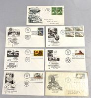 Top side view of all seven vintage first day issue envelopes with cachets and stamps, arranged in two rows displaying cachets and stamps clearly.