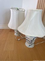 Two Aberle pottery table lamps with mismatched white fabric shades on wooden floor.
