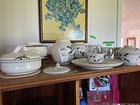 Full display of pottery showing lidded casseroles, vases, mugs, and serving dishes with tags visible.