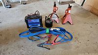 Photo of the entire lot including battery charger, oil can, jumper cables, and jack stands