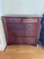 Front view of wood dresser with five drawers showing overall condition and drawer details.