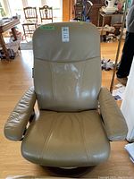 Front view of recliner showing leather upholstery, armrests, and green lot tag