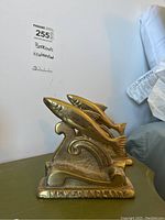 Single brass fish bookend angled slightly showing fish jumping over wave base with Newfoundland inscription