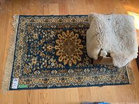 Photo showing the navy blue medallion patterned rug with fringe and sheepskin cover on top of a box