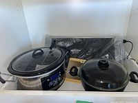 Hamilton Beach slow cooker, black stock pot with Pyrex lid, VillaWare warming tray in plastic packaging