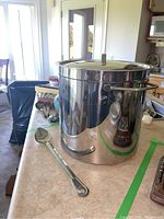 Full view of the stock pot with lid and the serving spoon lying beside it on a countertop.