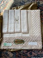 Ulster Irish Linen 52x52 inch tablecloth with lace edging and intricate knit patterns, folded with tags and original logo label visible.