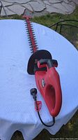 Full view of Craftsman electric hedge trimmer on white table with visible power cord and red and black handle.
