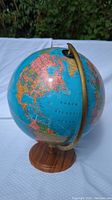 Full side view of the globe showing North and South America with wooden stand and brass meridian.