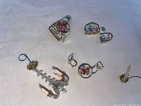 Miniature Limoges dollhouse items including a baby grand piano, loveseat, armchair, side table, sconce, chandelier, and small table and chairs, displayed on a light surface