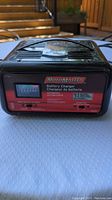 Front view of black and red Motomaster battery charger showing label and controls