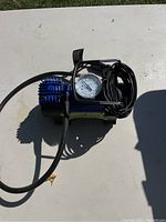 Top view of the new certified car air pump showing gauge, cord, and air hose coiled on the unit.