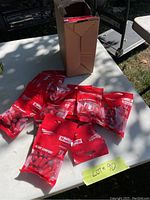 Lot showing 10 packs of Milwaukee red foam ear plugs sealed in original packaging on a table with a cardboard box.