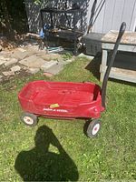 Red Radio Flyer kids wagon sitting on grass shown from side