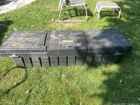 Top view of closed large black heavy duty truck box showing three segmented lids with push button latches and ribbed reinforcement design.