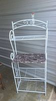 Full view of white metal baker's rack showing decorative curved design and tiers