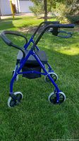 Side view of the royal blue rollator walker showing the padded seat, hand brakes, and large wheels