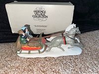 Front and side view of the Heritage Village Collection 'Sleighride' porcelain figurine showing the sleigh, horse, and two figures.