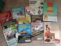 Photo showing multiple magazine covers including Popular Mechanics, Science & Mechanics, Consumer Reports, Western Auto, and Radio Shack catalogs all from late 1960s period.
