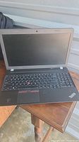 Front view of Lenovo ThinkPad laptop open on table, showing screen and keyboard with TrackPoint and Lenovo branding.