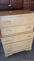Photo of front view of two-piece vintage light colored children's chest of drawers with wooden handles, showing both sections stacked