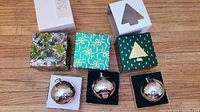 Lot of three silver plated Christmas bells by Wallace, each displayed in original decorated boxes on wooden floor.