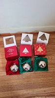 Three silver plated Wallace annual sleigh bell ornaments in velvet pouches and original boxes, arranged side by side on wooden floor.