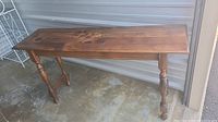 Full side view of dark wood rectangular sofa table showing turned legs and stretcher support.