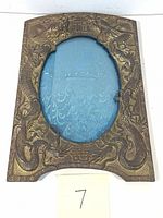 Full view of the front brass picture frame with detailed snake or dragon embossing and oval photo slot.