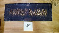 Photo of rectangular hand painted plaster relief showing pilgrims on horseback in procession, with a dark background and gold toned figures.